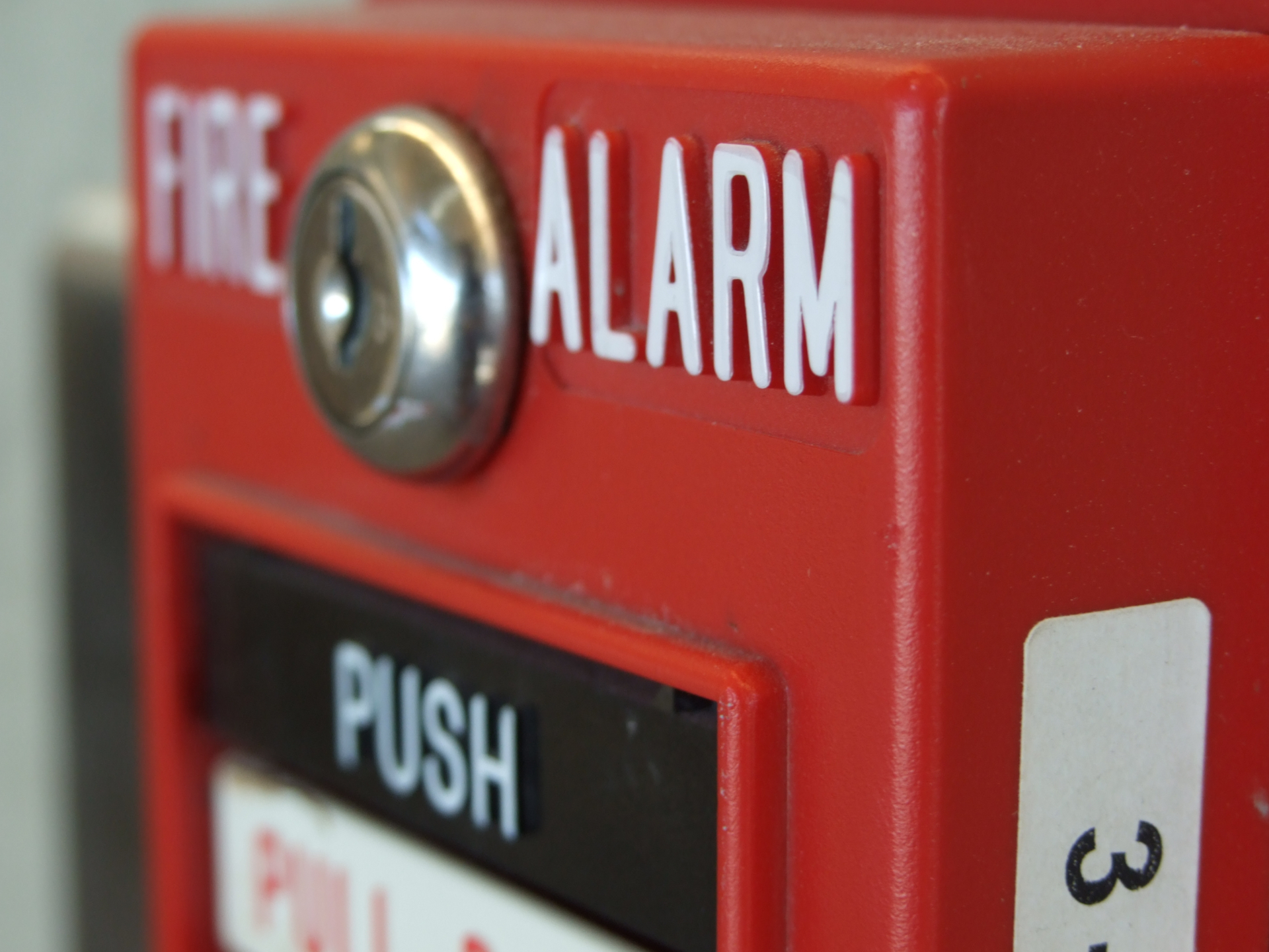 Close-up of a red fire alarm pull station with the words "FIRE ALARM" and "PUSH" visible.